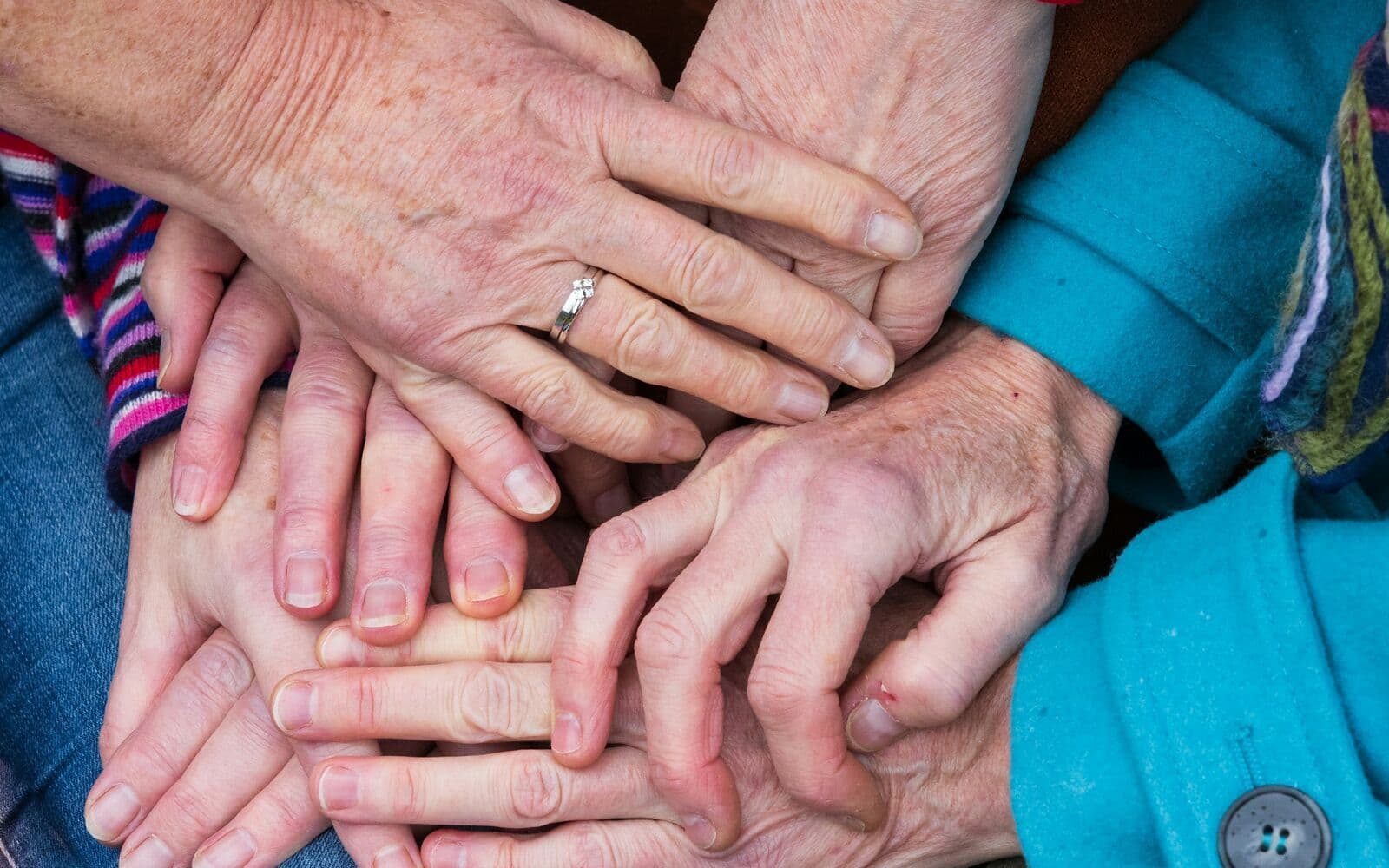 Des mains de personnes âgées posées les unes sur les autres, en signe de solidarité.