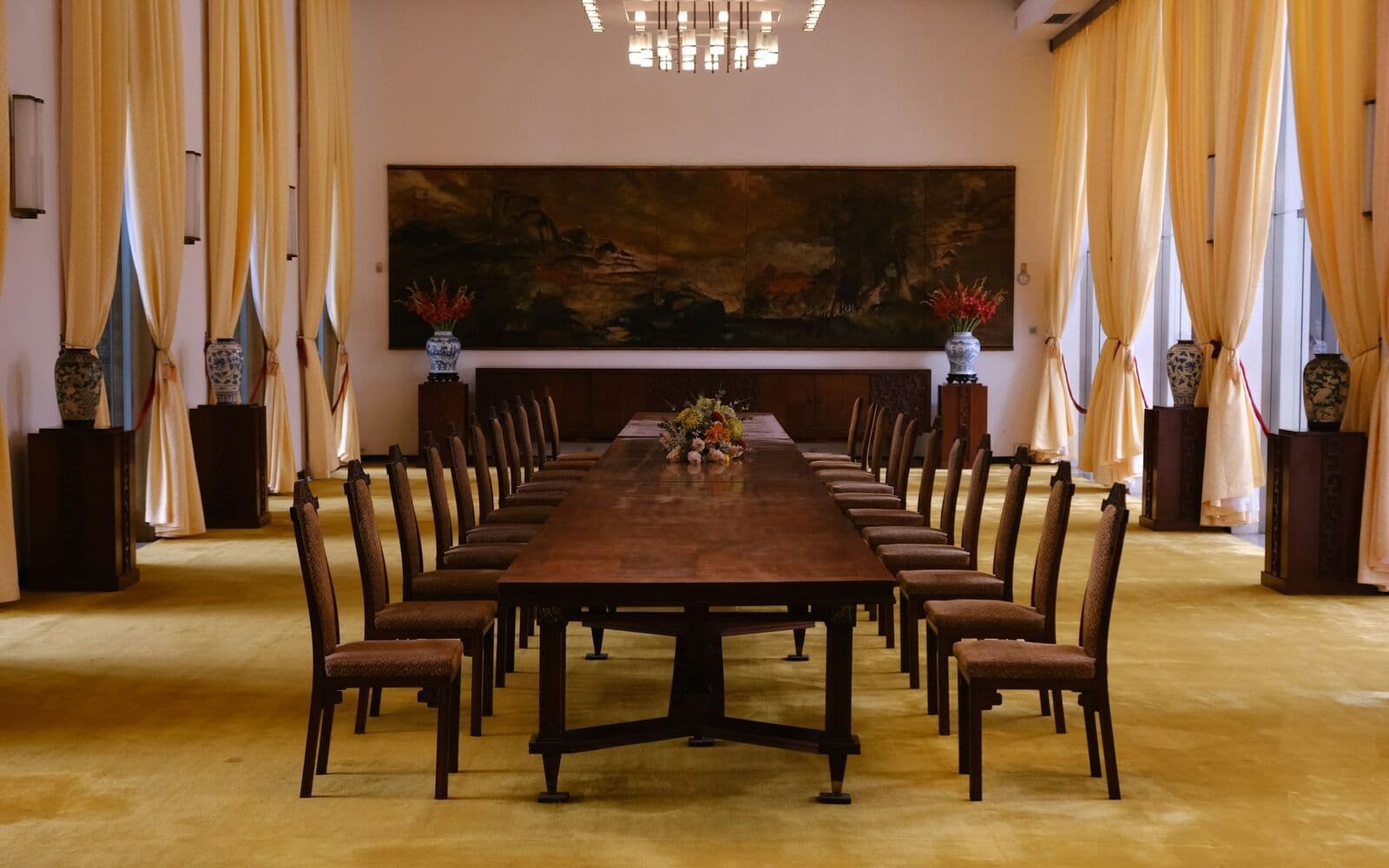 Une salle de réunion avec une longue table en bois et des chaises alignées.
